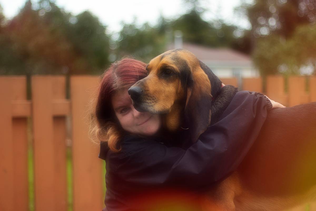Woman hugging her emotional support dog on couch